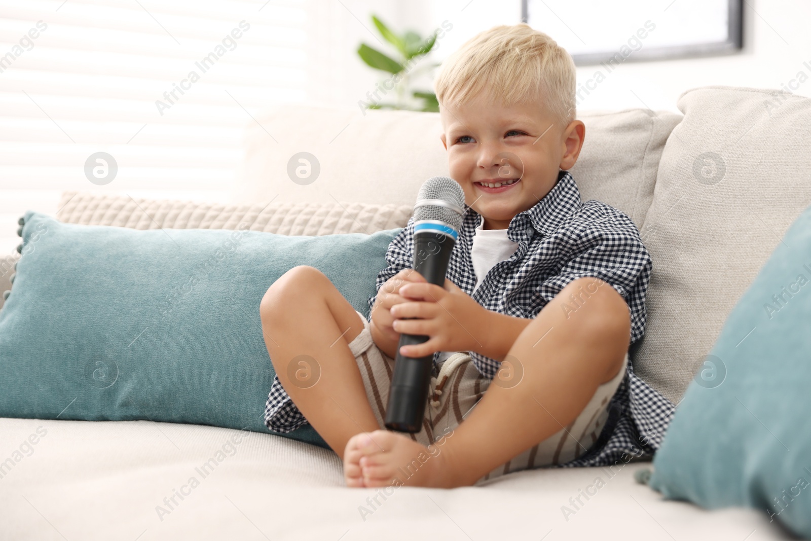Cute little boy with microphone on sofa at home Photo of Cute little boy with microphone on sofa at home