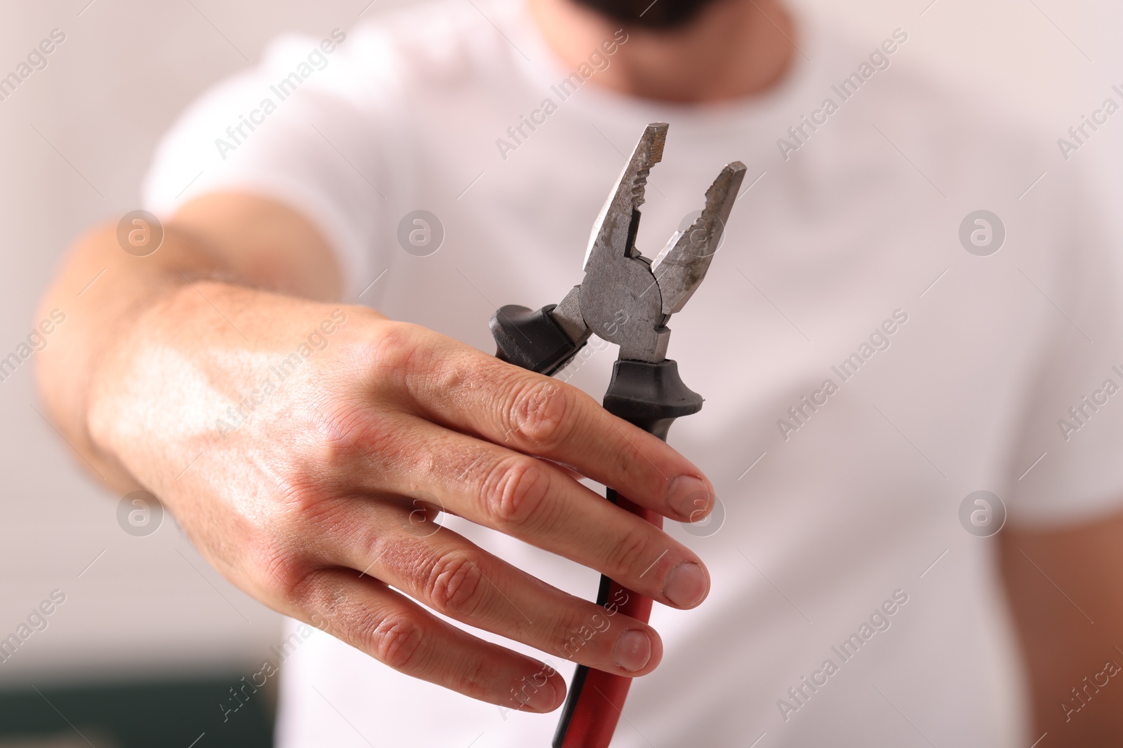Photo of Closeup view of man with pliers indoors