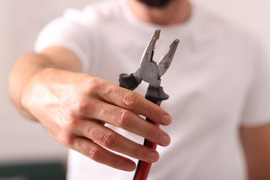 Photo of Closeup view of man with pliers indoors