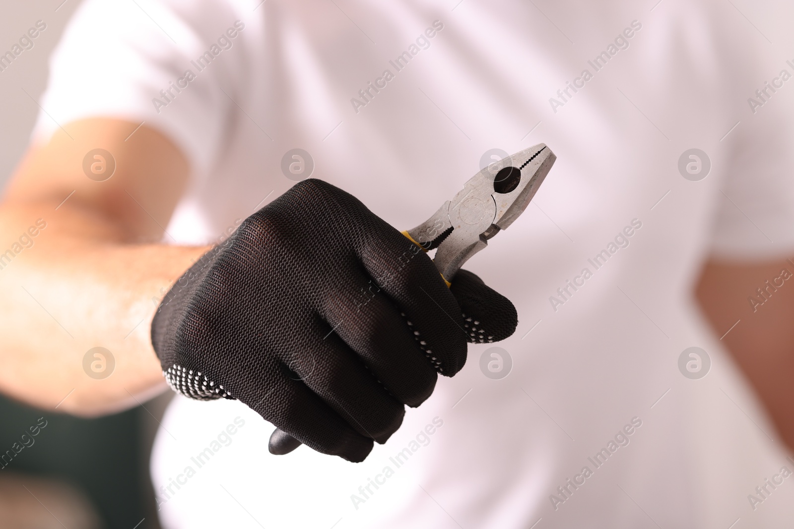 Photo of Man in glove holding pliers indoors, closeup