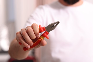 Photo of Closeup view of man with pliers indoors