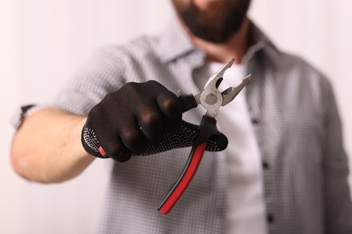 Photo of Man in glove holding pliers indoors, closeup