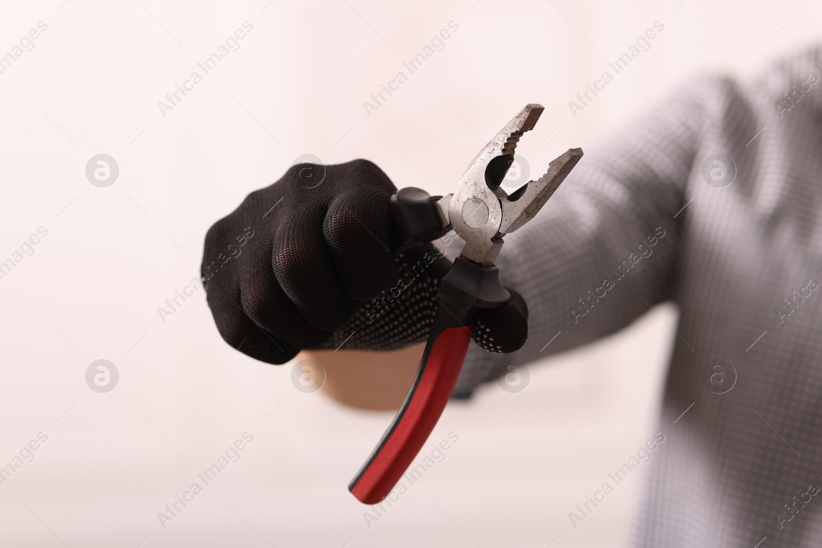 Photo of Man in glove holding pliers indoors, closeup