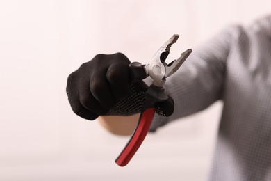 Photo of Man in glove holding pliers indoors, closeup