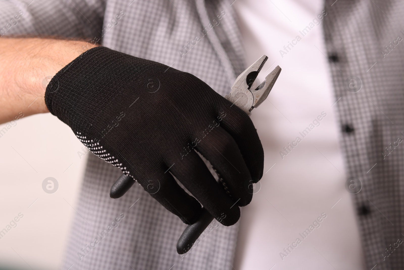 Photo of Man in glove holding pliers indoors, closeup