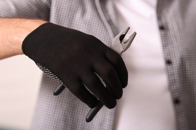 Photo of Man in glove holding pliers indoors, closeup