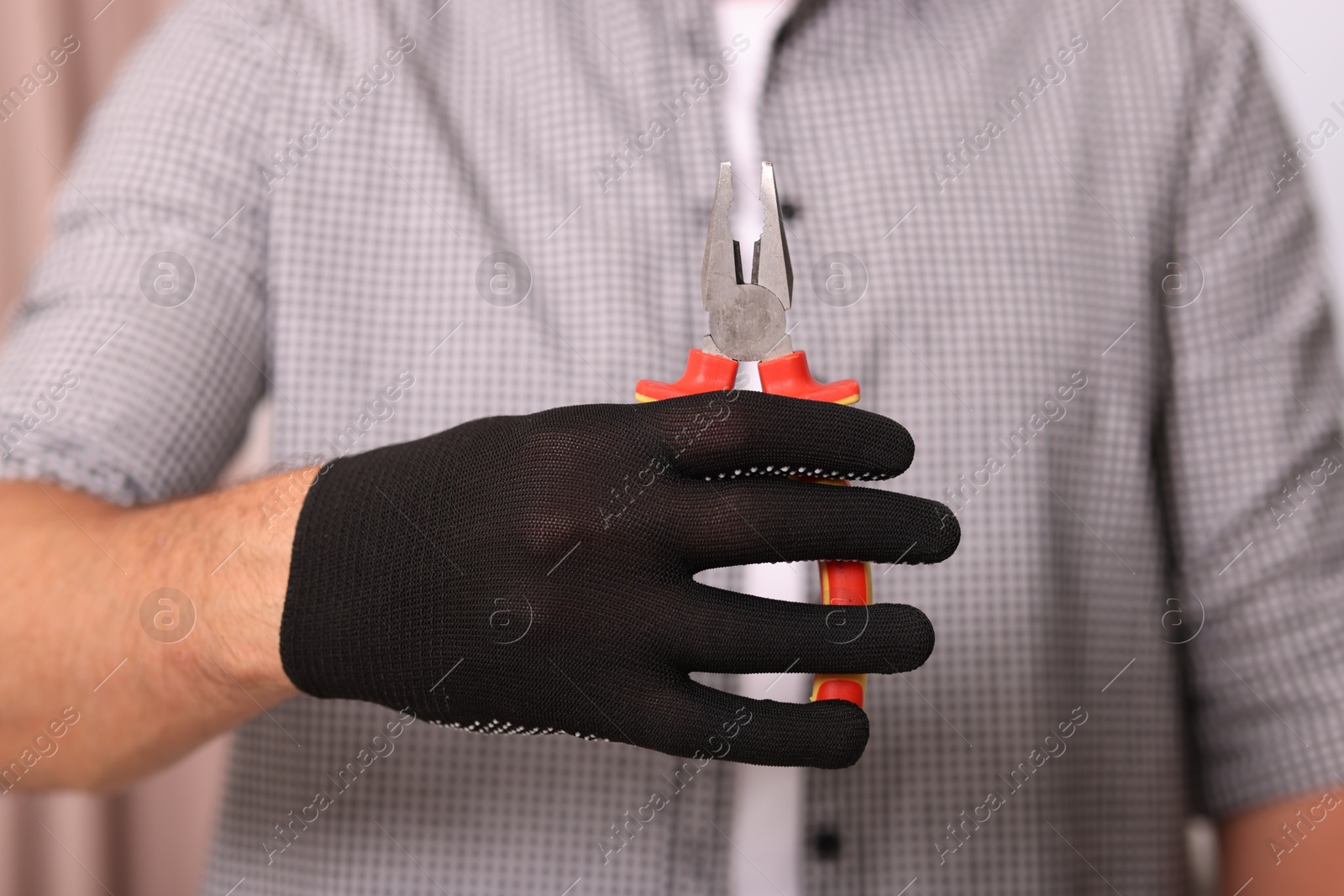 Photo of Man in glove holding pliers indoors, closeup