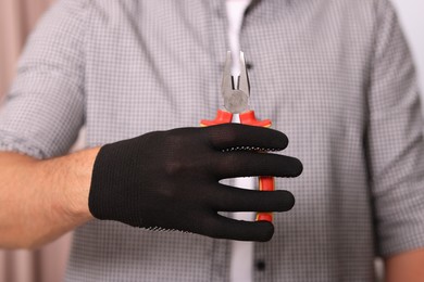 Photo of Man in glove holding pliers indoors, closeup