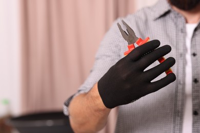Photo of Man in glove holding pliers indoors, closeup. Space for text