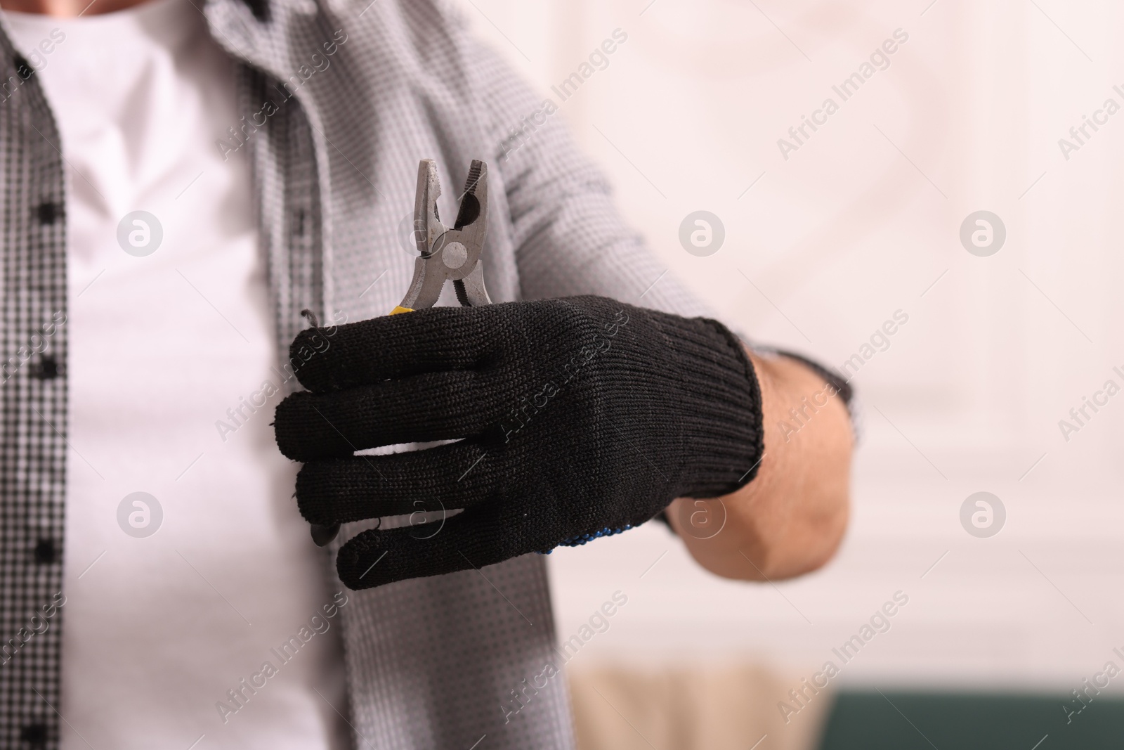 Photo of Man in glove holding pliers indoors, closeup