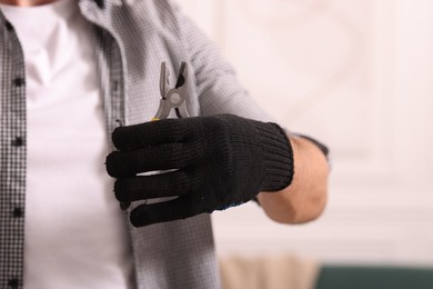 Photo of Man in glove holding pliers indoors, closeup