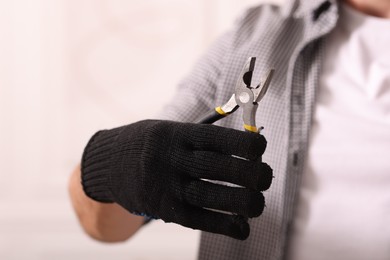 Photo of Man in glove holding pliers indoors, closeup