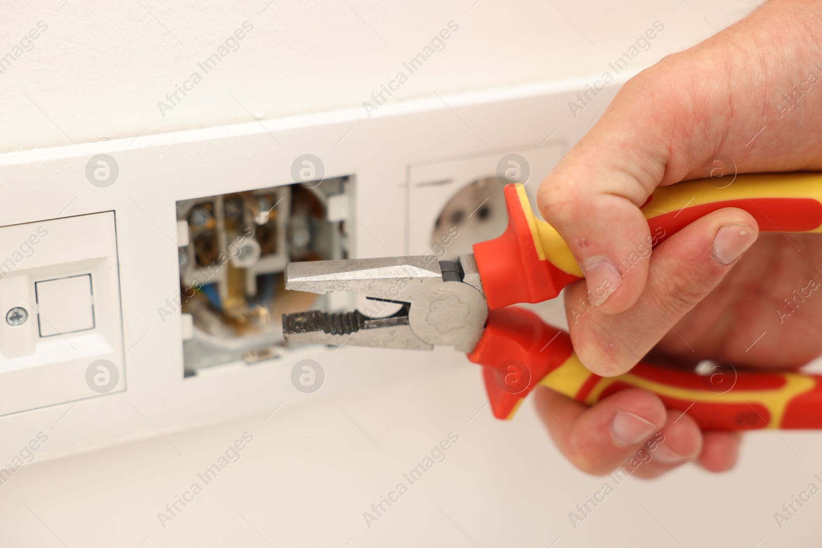 Photo of Man fixing power sockets with pliers indoors, closeup
