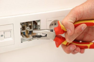 Photo of Man fixing power sockets with pliers indoors, closeup