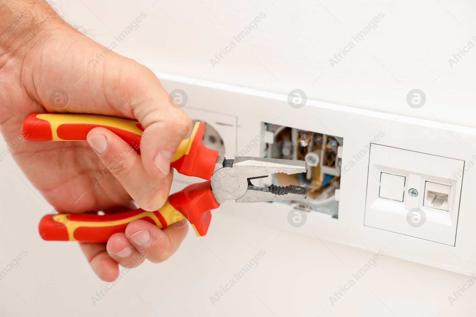 Photo of Man fixing power sockets with pliers indoors, closeup