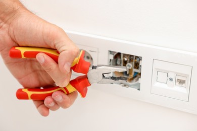 Photo of Man fixing power sockets with pliers indoors, closeup