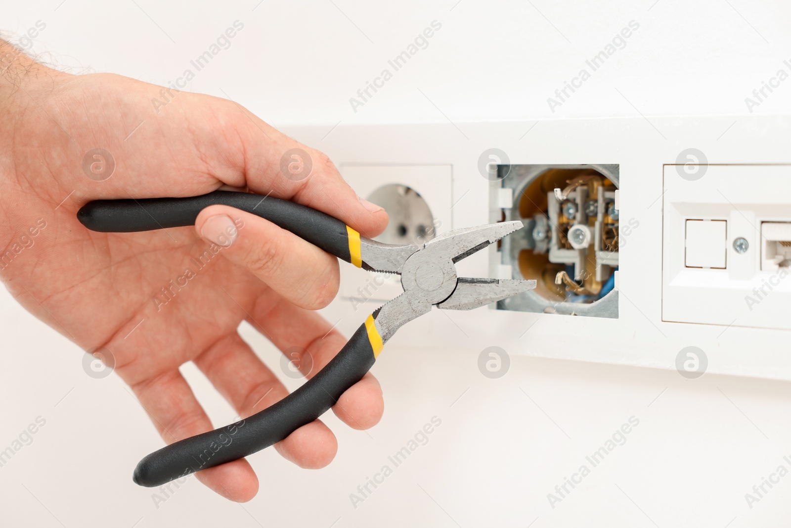 Photo of Man fixing power sockets with pliers indoors, closeup