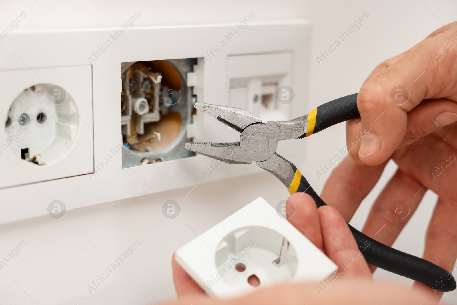 Photo of Man fixing power sockets with pliers indoors, closeup