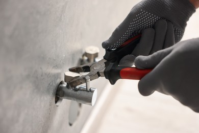Photo of Man fixing water valve with pliers indoors, closeup