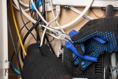Photo of Man fixing heating radiator with pliers indoors, closeup