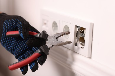 Photo of Man fixing power sockets with pliers indoors, closeup