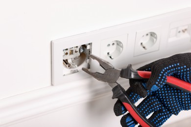 Photo of Man fixing power sockets with pliers indoors, closeup