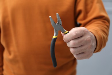 Photo of Closeup view of man with pliers indoors
