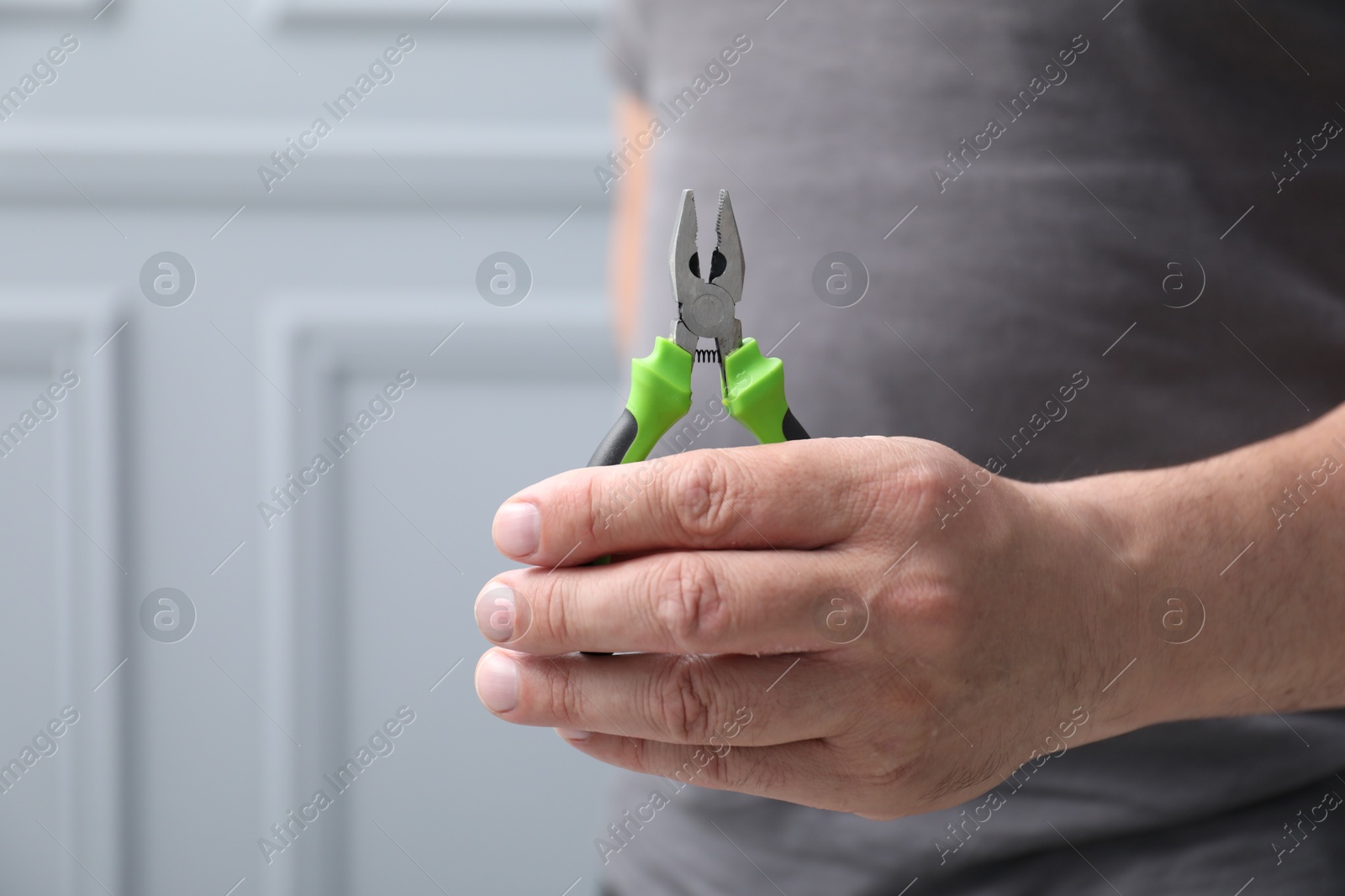 Man with pliers indoors, space for text Photo of Man with pliers indoors, space for text