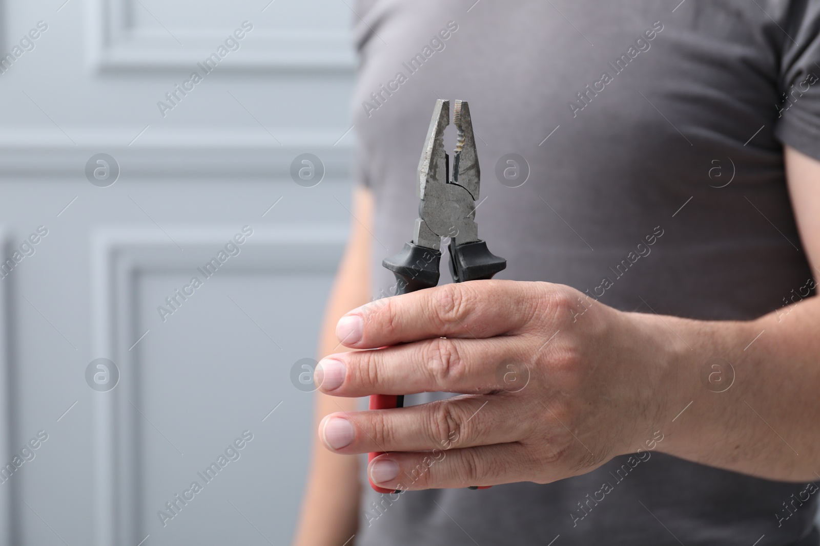 Man with pliers indoors, space for text Photo of Man with pliers indoors, space for text