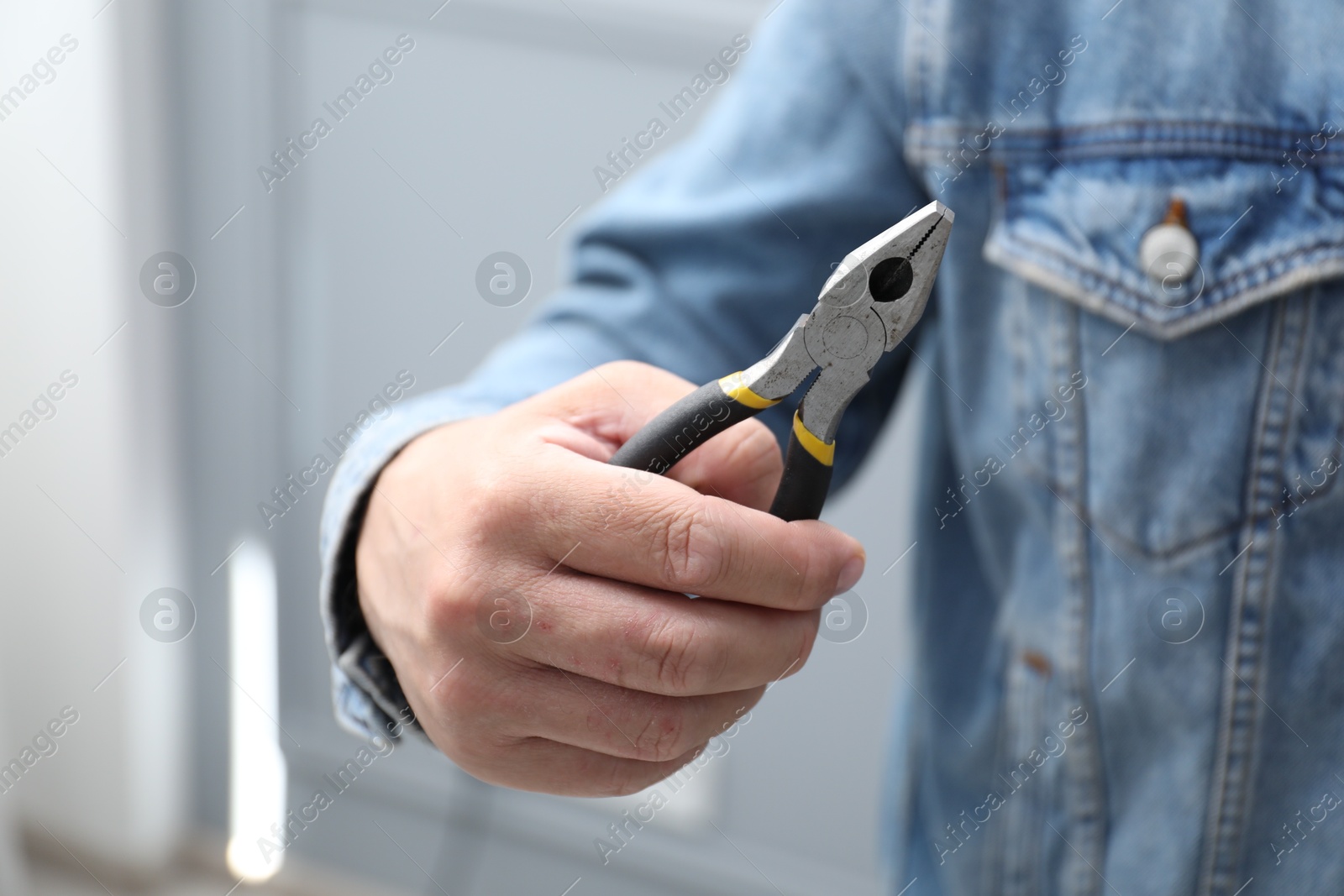 Closeup view of man with pliers indoors Photo of Closeup view of man with pliers indoors