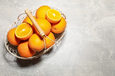 Photo of Fresh ripe oranges in basket on grey background, top view. Space for text