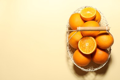 Photo of Fresh ripe oranges in basket on beige background, top view. Space for text