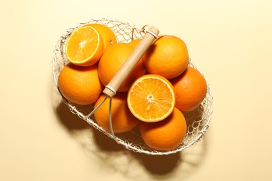 Photo of Fresh ripe oranges in basket on beige background, top view