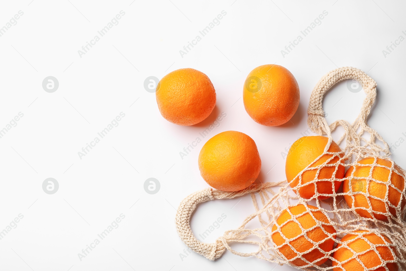 Fresh ripe oranges and string bag on white background, flat lay. Space for text Photo of Fresh ripe oranges and string bag on white background, flat lay. Space for text