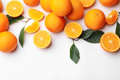 Photo of Fresh ripe oranges and green leaves on white background, flat lay. Space for text
