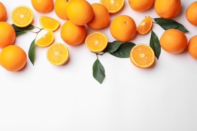 Photo of Fresh ripe oranges and green leaves on white background, flat lay. Space for text
