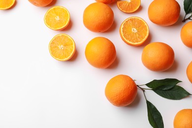 Photo of Fresh ripe oranges and green leaves on white background, flat lay. Space for text
