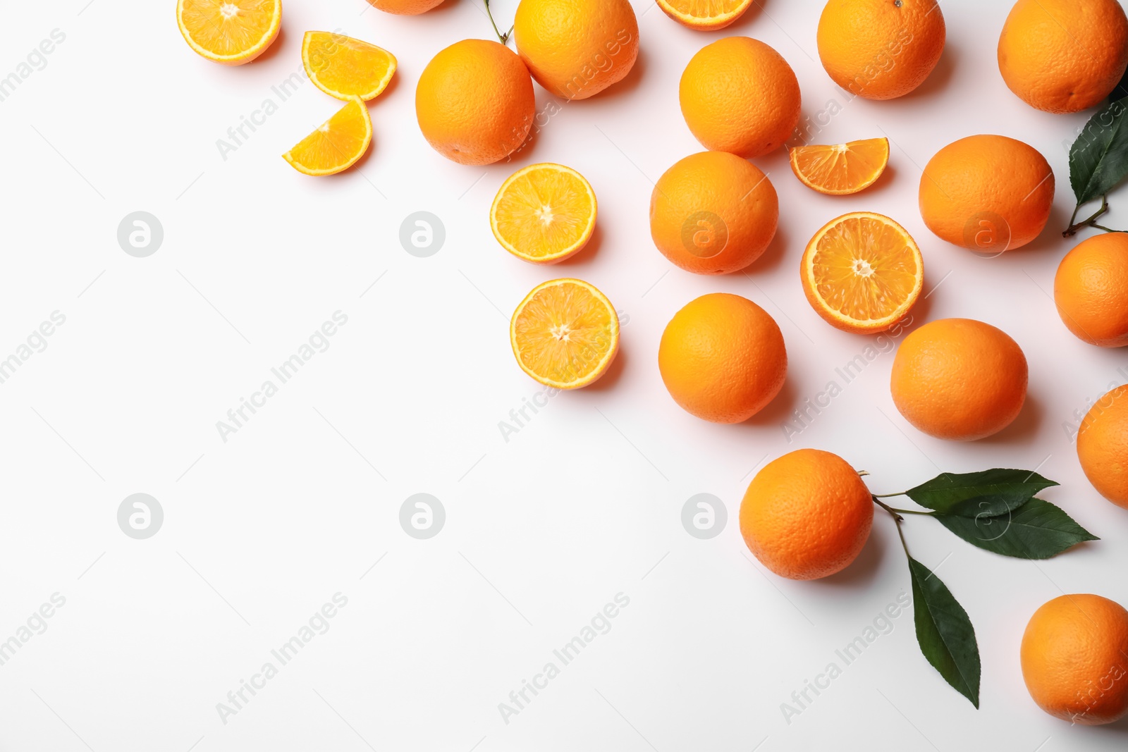 Fresh ripe oranges and green leaves on white background, flat lay. Space for text Photo of Fresh ripe oranges and green leaves on white background, flat lay. Space for text