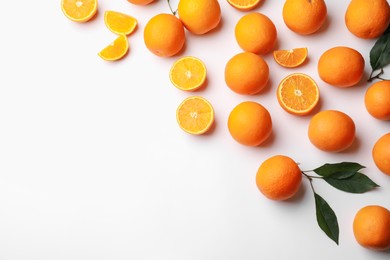 Photo of Fresh ripe oranges and green leaves on white background, flat lay. Space for text