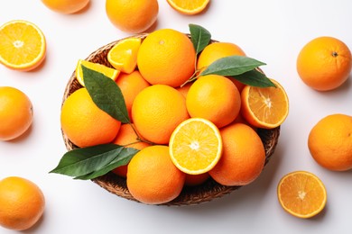 Photo of Fresh ripe oranges and green leaves on white background, flat lay