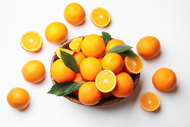 Photo of Fresh ripe oranges and green leaves on white background, flat lay
