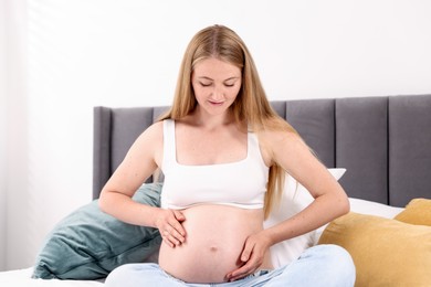 Photo of Beautiful pregnant woman on bed at home