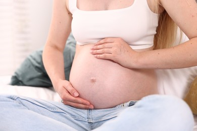 Photo of Beautiful pregnant woman on bed at home, closeup