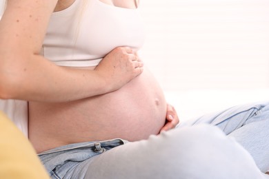 Photo of Beautiful pregnant woman on bed at home, closeup. Space for text