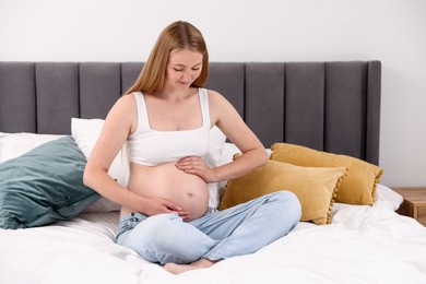 Photo of Beautiful pregnant woman on bed at home