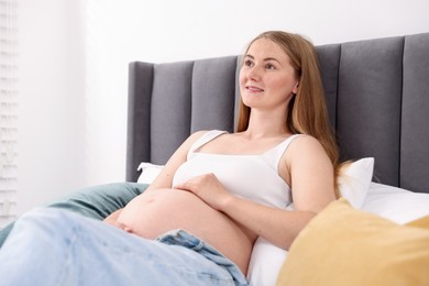 Photo of Beautiful pregnant woman on bed at home. Space for text