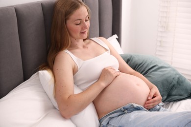Photo of Beautiful pregnant woman on bed at home