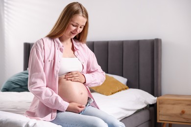 Photo of Beautiful pregnant woman on bed at home. Space for text