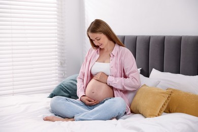 Photo of Beautiful pregnant woman on bed at home