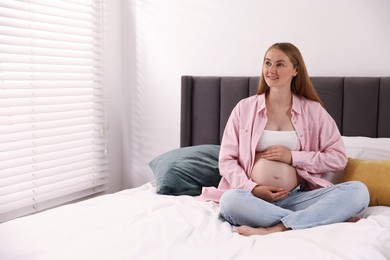 Photo of Beautiful pregnant woman on bed at home. Space for text